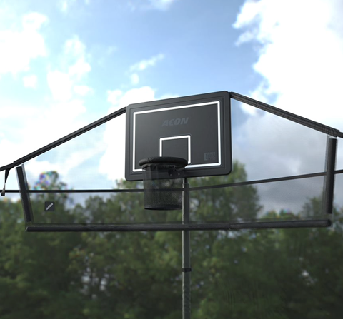 Utomhusbild av Acon basketkorg för rund studsmatta med bollfångarnät sedd underifrån, som visar blå himmel och omgivande träd och moln.