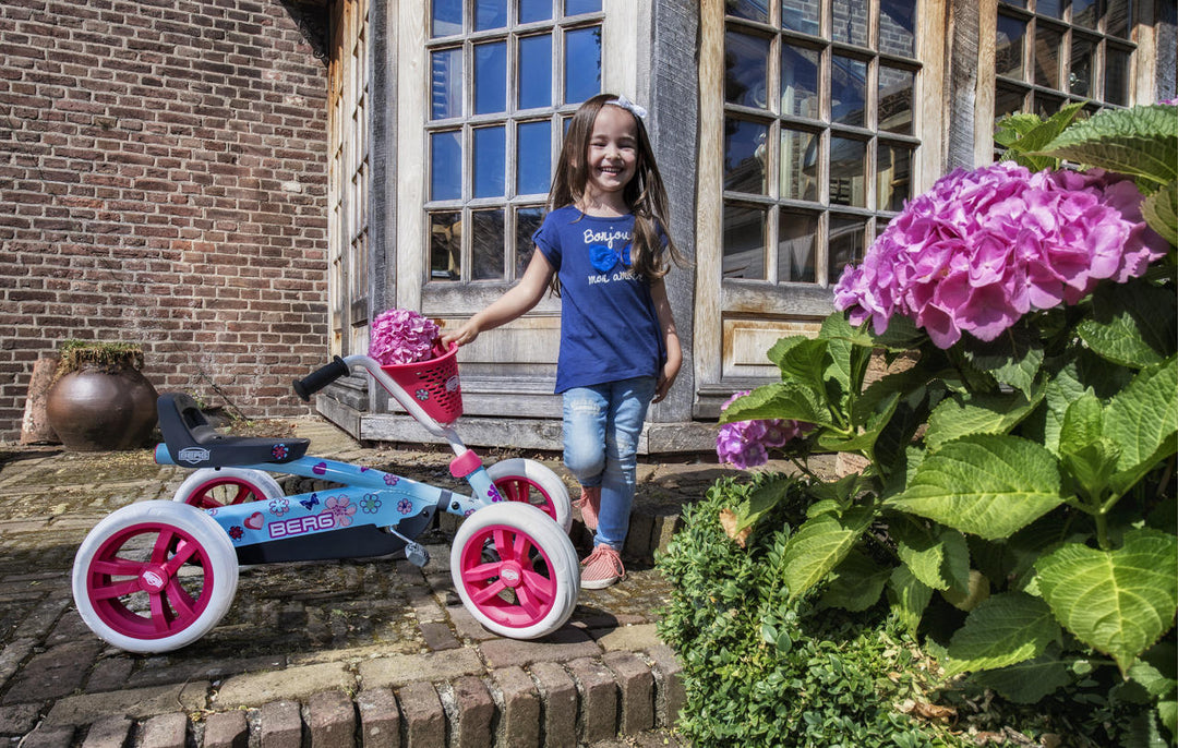 Tjej poserar glatt utanför framför huset bredvid BERG Buzzy Bloom trampbil