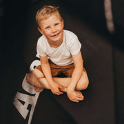 En skrattande pojke sitter på en Acon studsmatta.